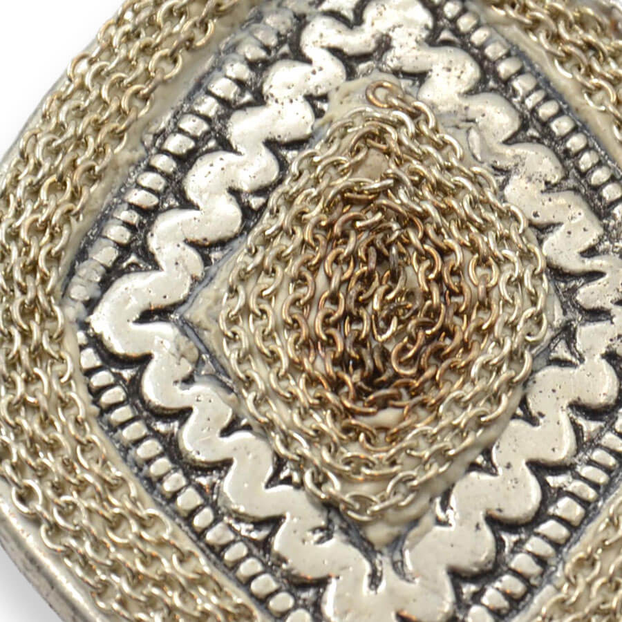Colgante metálico plateado con relieves ornamentales